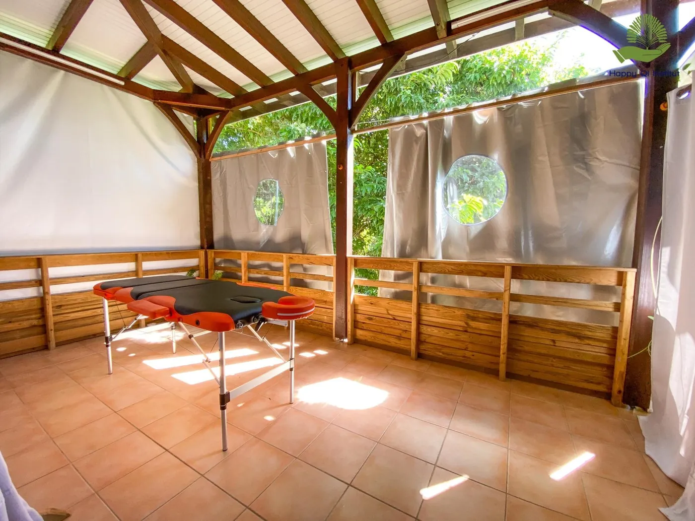 Carbet en bois ouvert sur le jardin, tables de massage installées