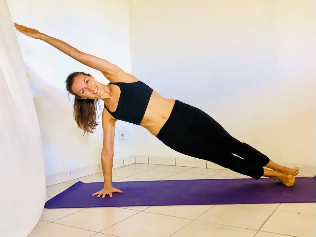 Déborah Dubreucq en posture de planche latérale sur un tapis de yoga